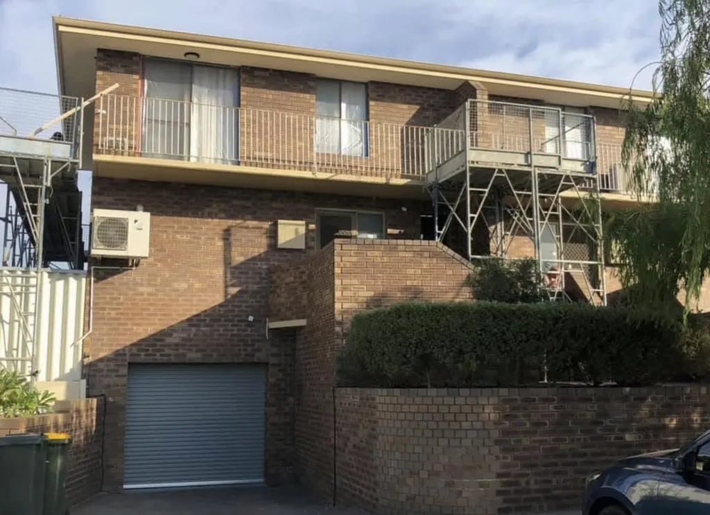 Brick apartment frontage before rendering, with scaffold