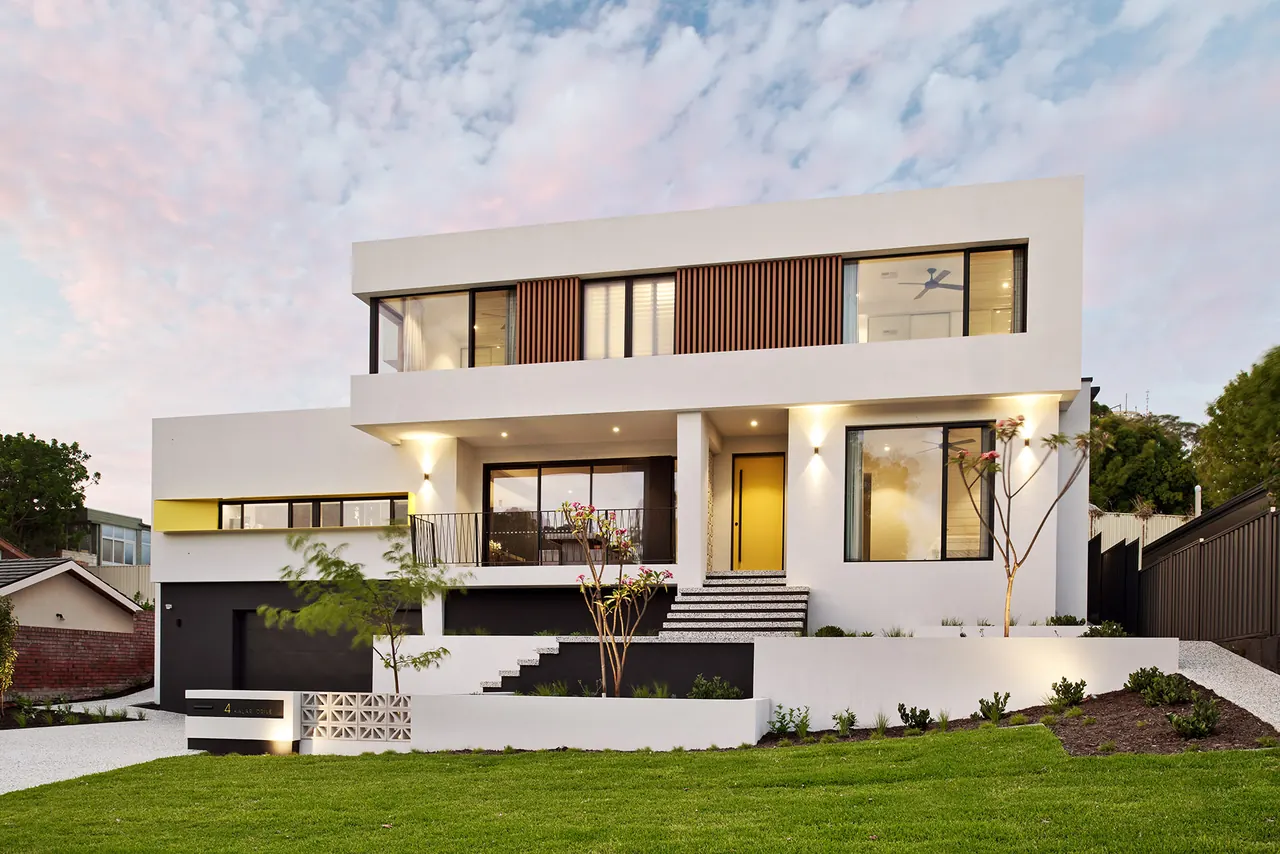 Completed modern two-storey home with white rendered facade at dusk