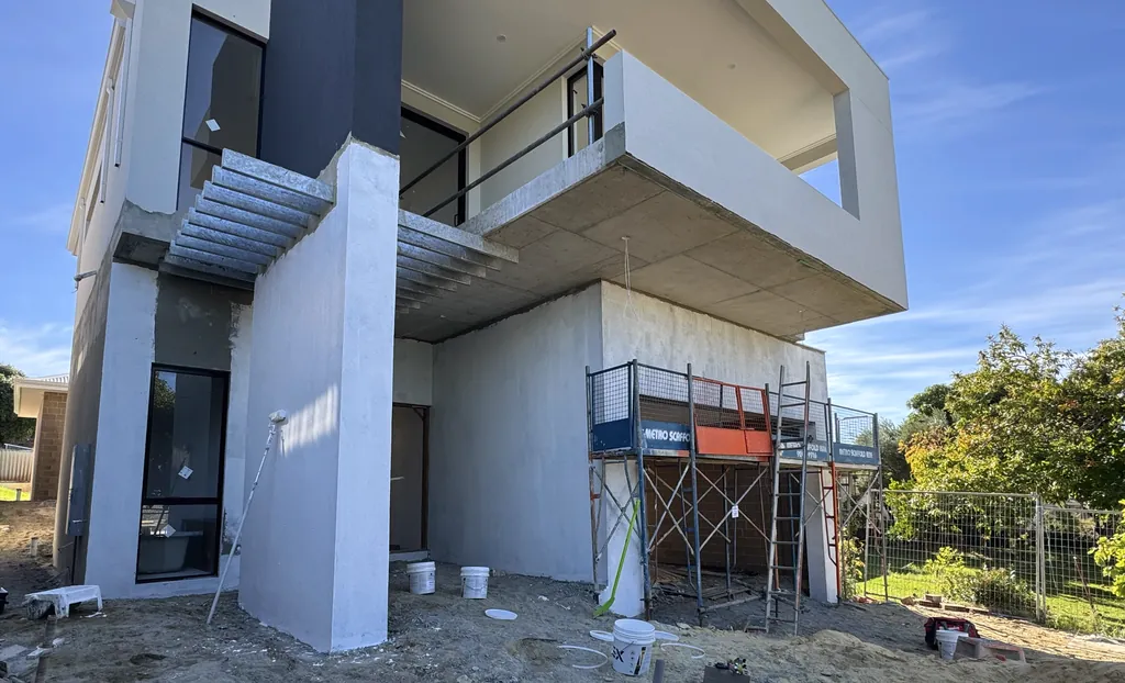 Two-storey home under scaffold with render being applied